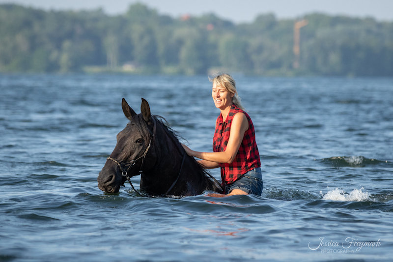Katja schwimmt mit ihrem Pferd im See